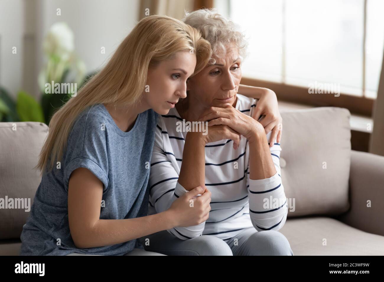 Grownup adult daughter soothes elderly mother shares her mental pain Stock Photo