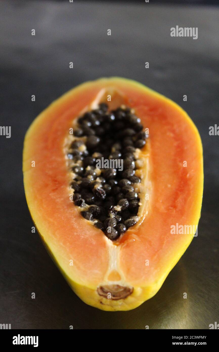 Vertical image of a cut half of a papaya fruit. Stock Photo