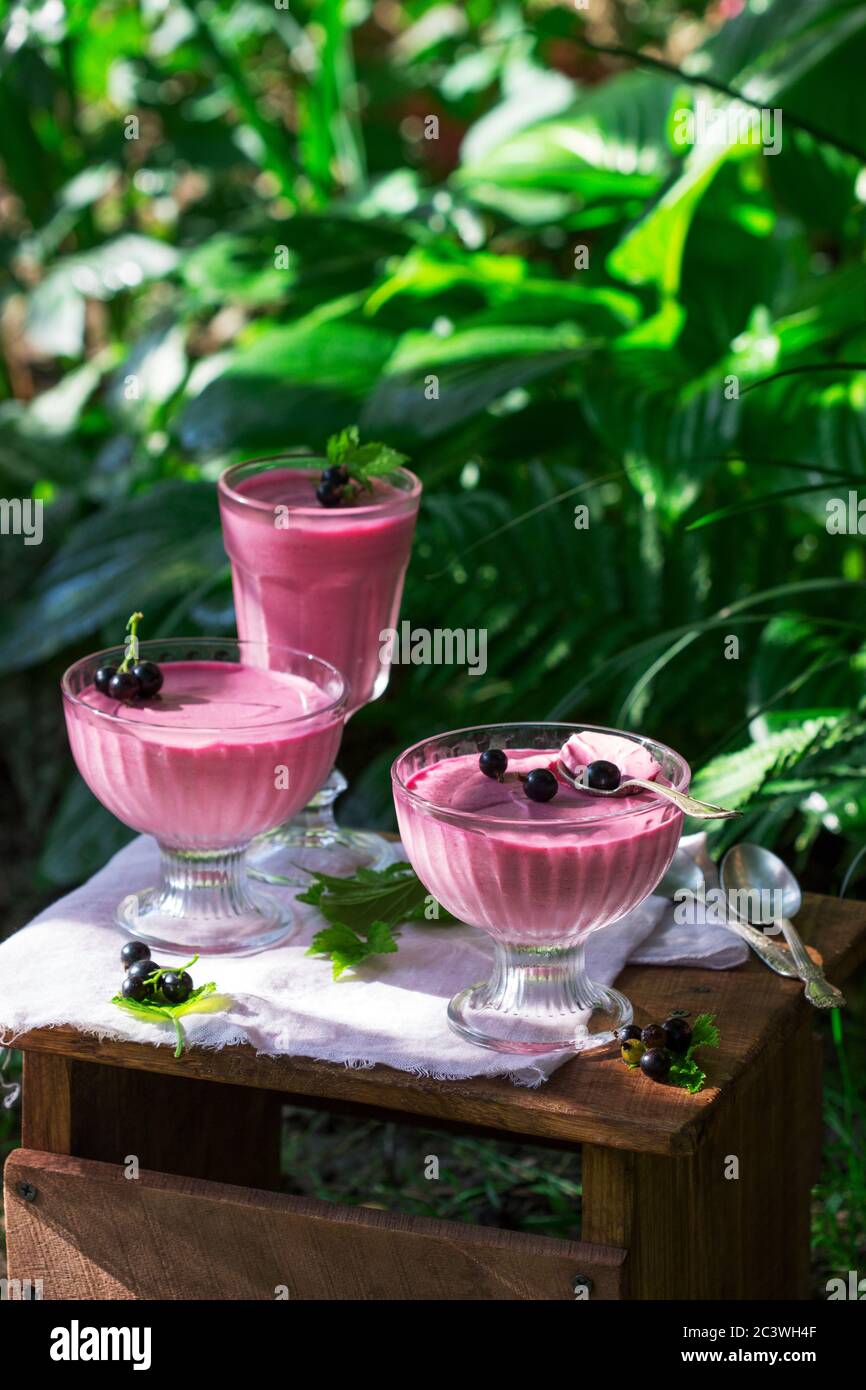 Berry mousse in glass vases on a wooden background in the garden. Stock Photo