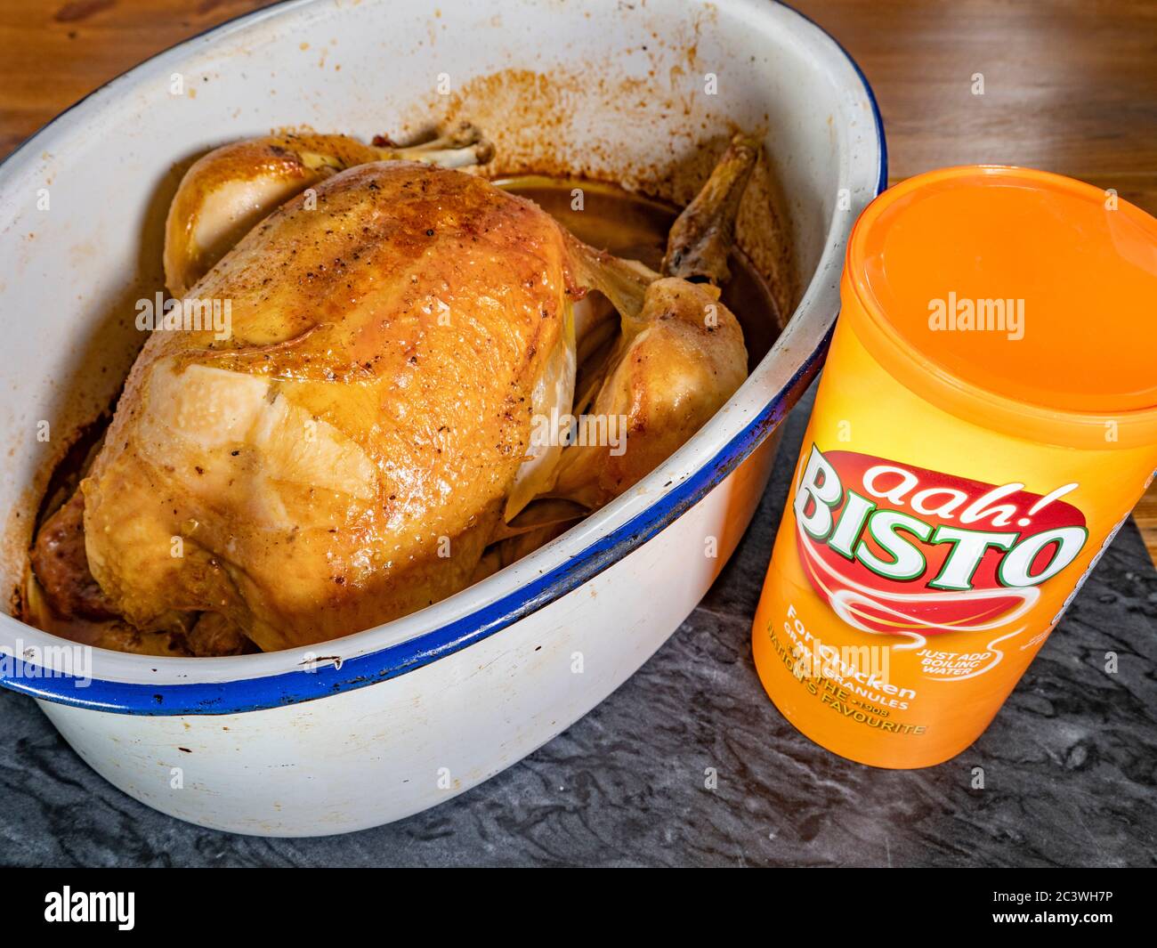 A tub of Bisto chicken gravy granules next to a freshly cooked whole
