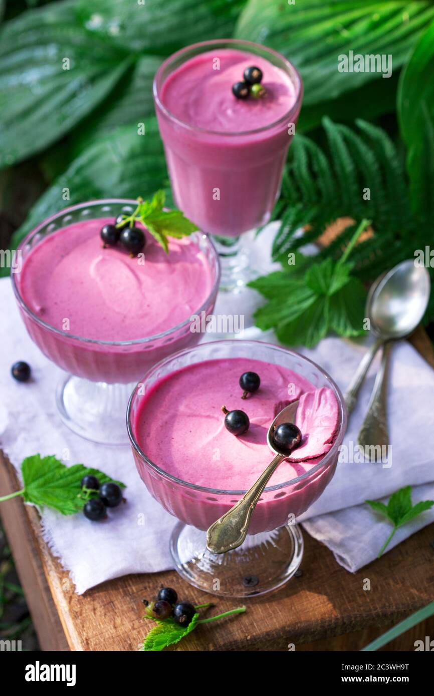 Berry mousse in glass vases on a wooden background in the garden. Stock Photo
