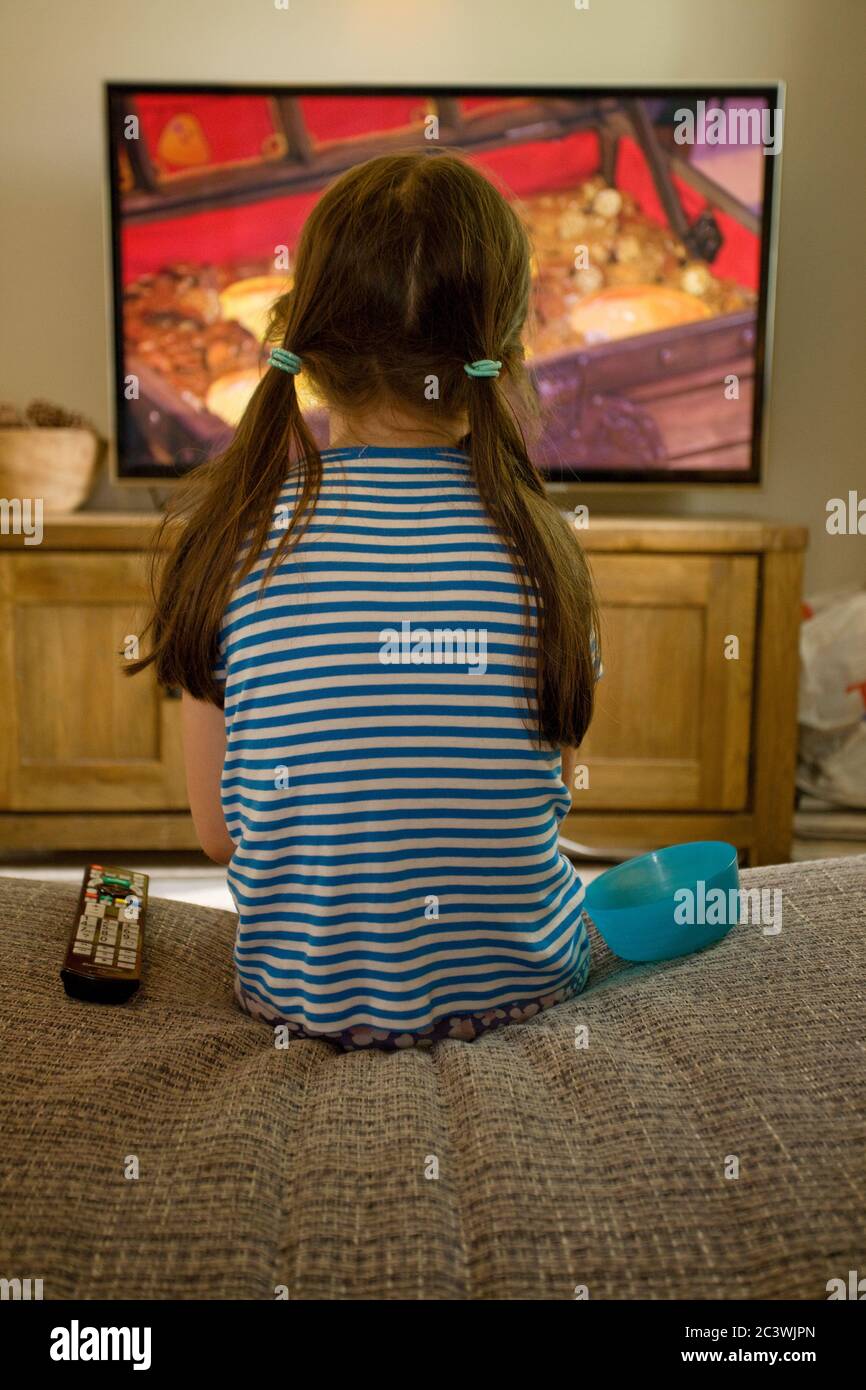 Young girl watching the television with her back turned Stock Photo