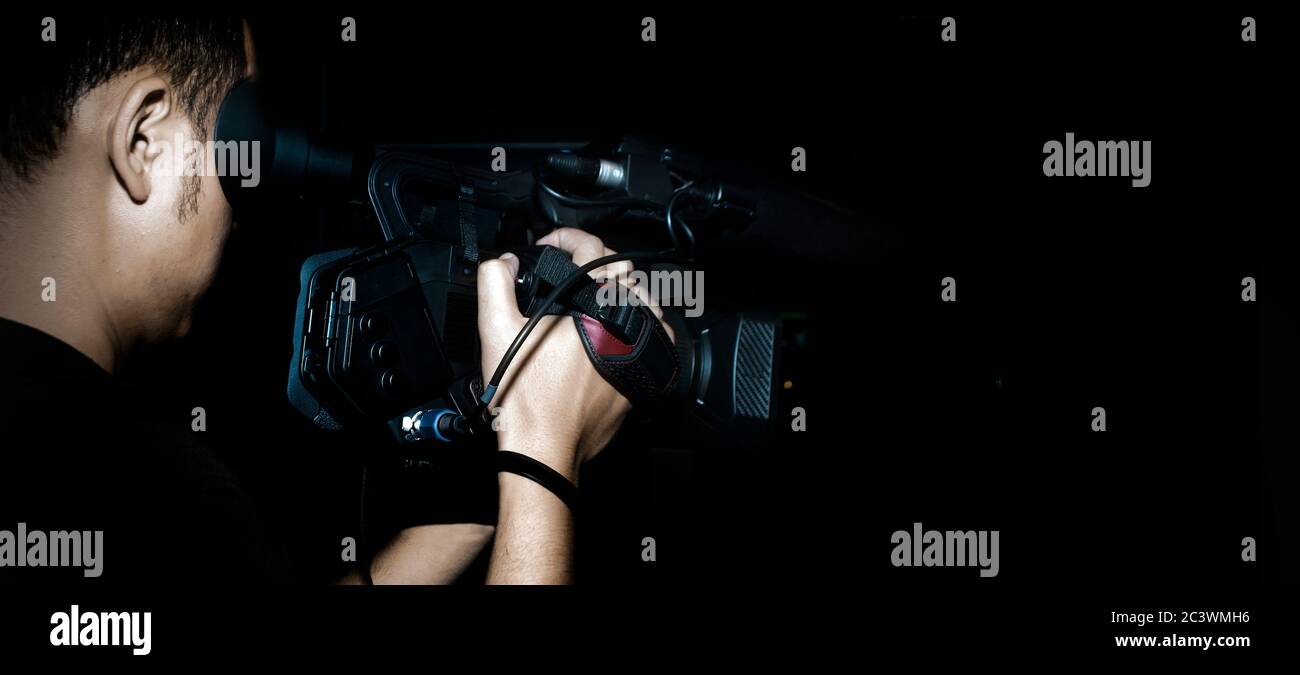 cameraman record movie with digital camera make clip in media production on dark background (banner size) Stock Photo
