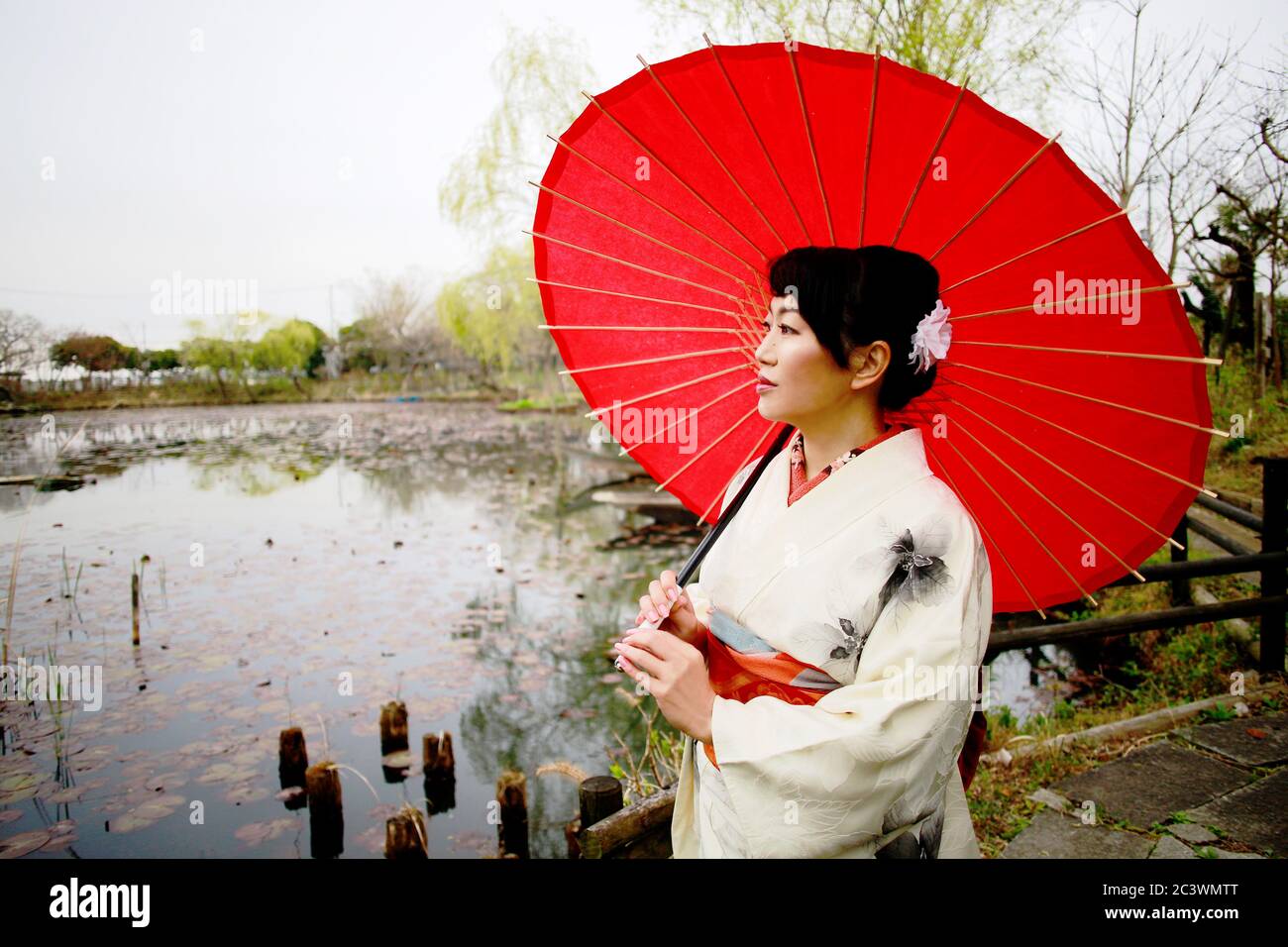 Portrait of Japanese woman wearing white kimono holds a red umbrella at