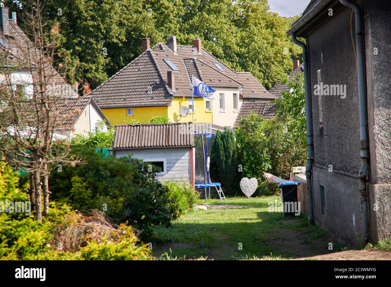 Bergarbeitersiedlung in Gelsenkirchen Hassel. In einam Garten hinter einem Bergarbeiter Haus weht die Flagge von dem Fussballverein Schalke 04. Stock Photo