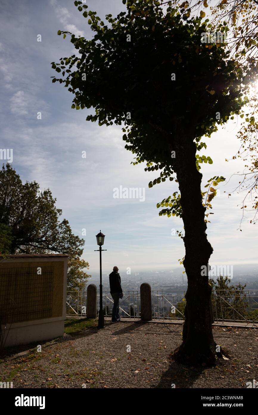 Dramatic silhouette of man standing on the Pöstlingberg viewing platform overlooking the town of Linz, Austria Stock Photo