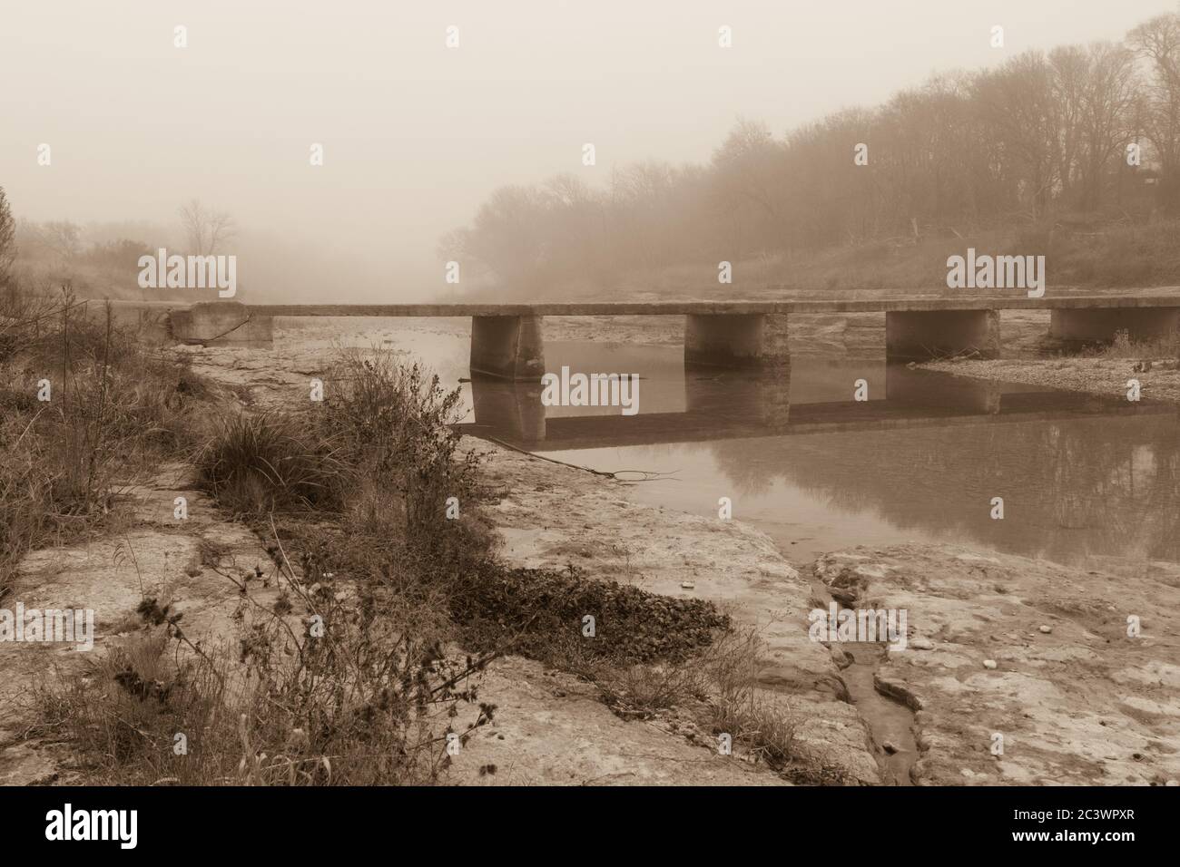 Old concrete bridge crossing the San Gabriel river on a foggy day sepia tone Stock Photo