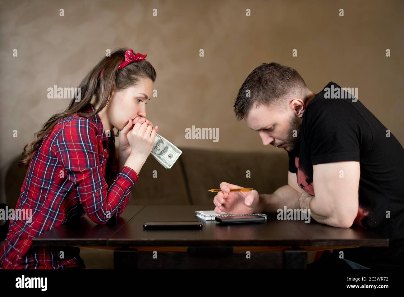 young couple counts money at the table and looks thoughtfully at the numbers Stock Photo