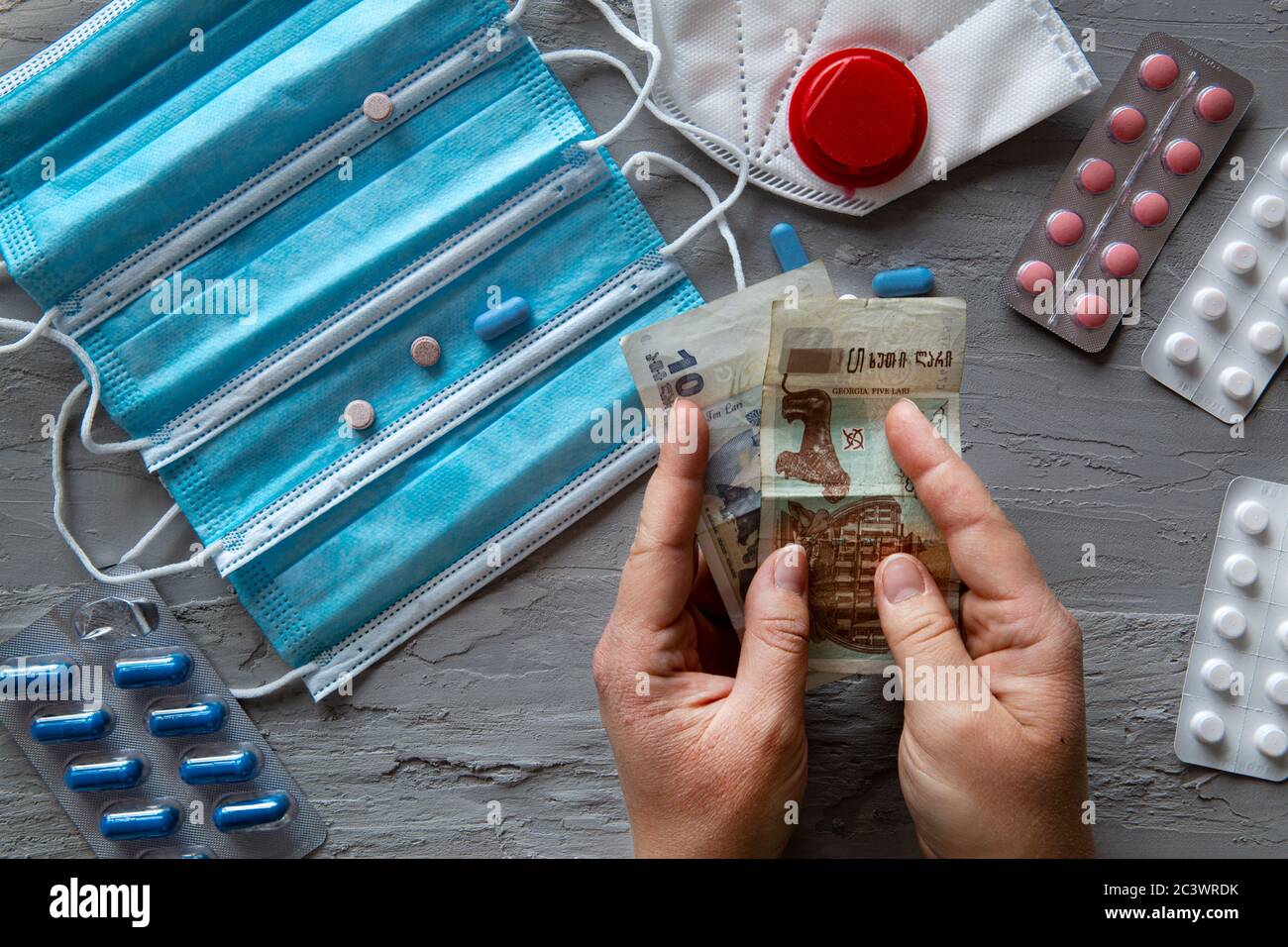Medical and health costs during coronavirus crisis. Epidemic covid-19 concept in Georgia. Lari banknotes and pills, top view. Stock Photo