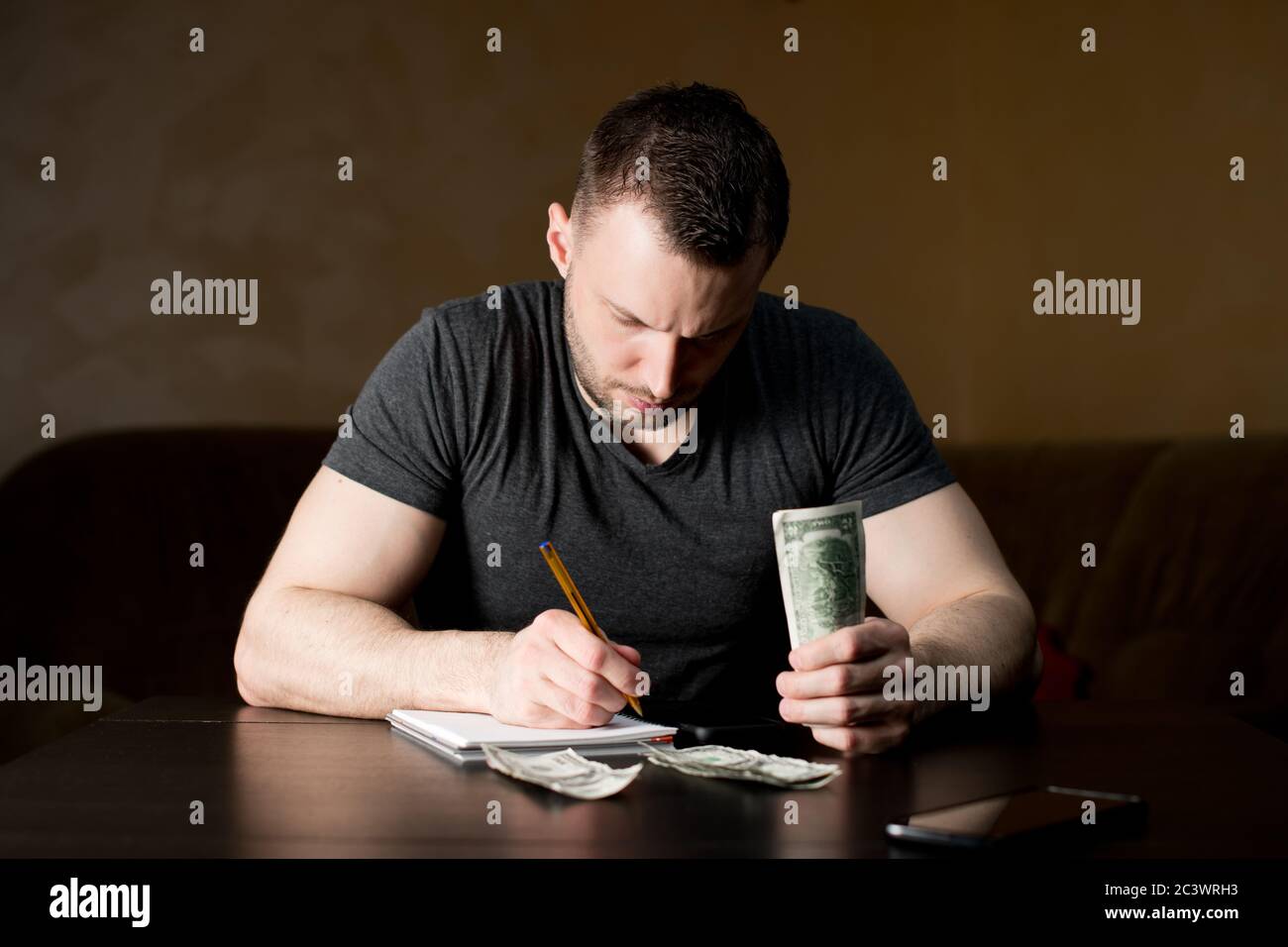 A man with a serious face counts the remaining funds and plans expenses Stock Photo