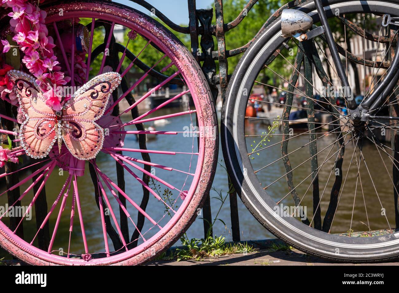 Wheels of decorated pink bicycle parked on a bridge over a canal in Amsterdam, Netherlands Stock Photo