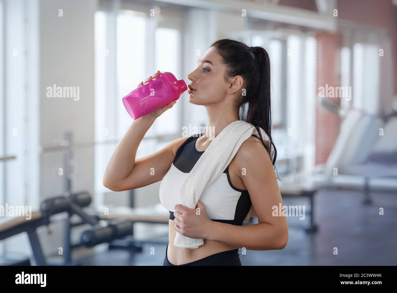 Beautiful woman resting after gym workout holding a plastic water