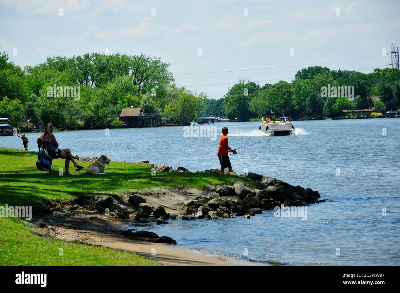 Young boy fishing from shoreline of Lions Park on the Fox River in Northern Illinois, USA. Stock Photo