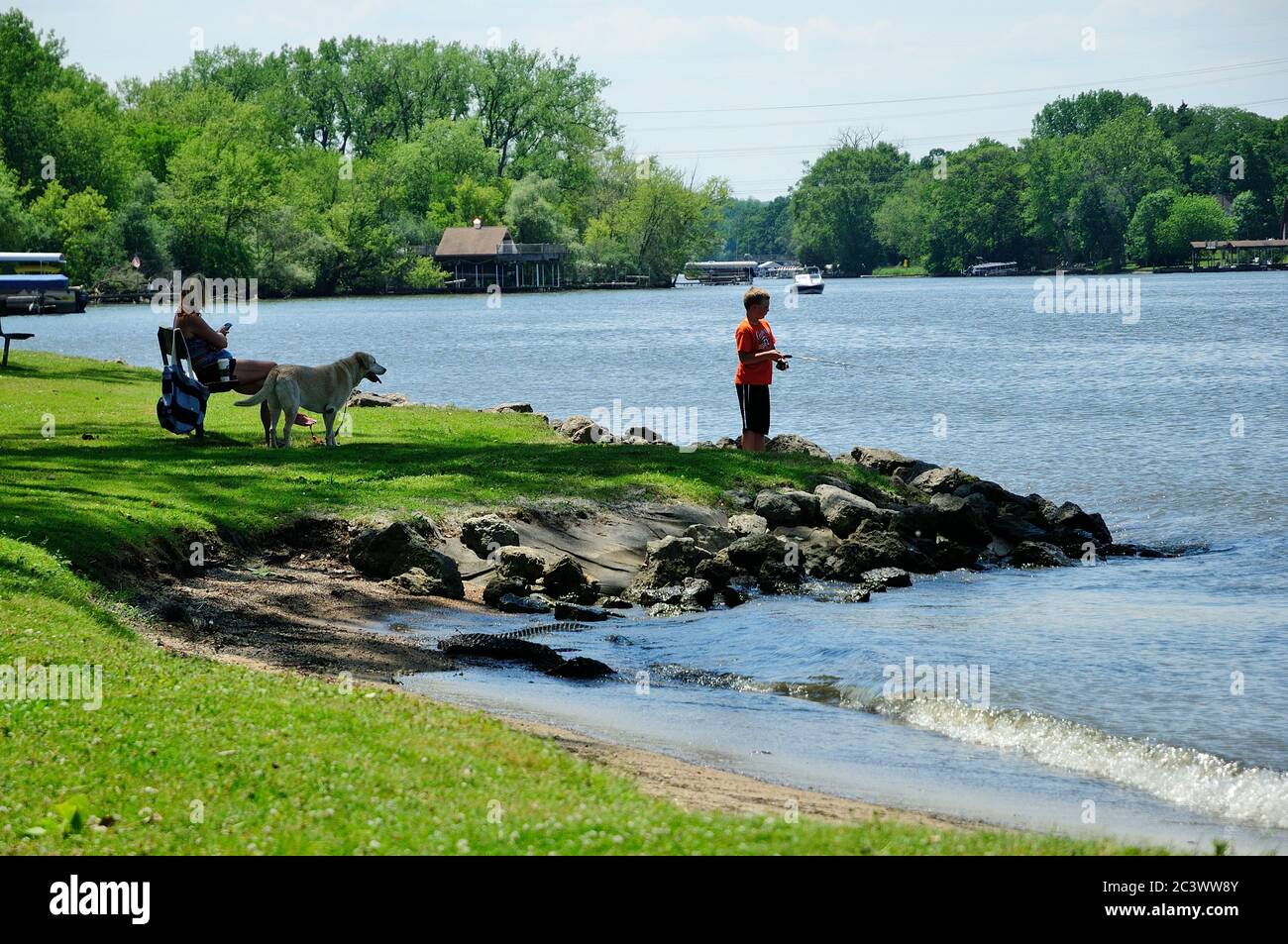 Young boy fishing from shoreline of Lions Park on the Fox River in Northern Illinois, USA. Stock Photo