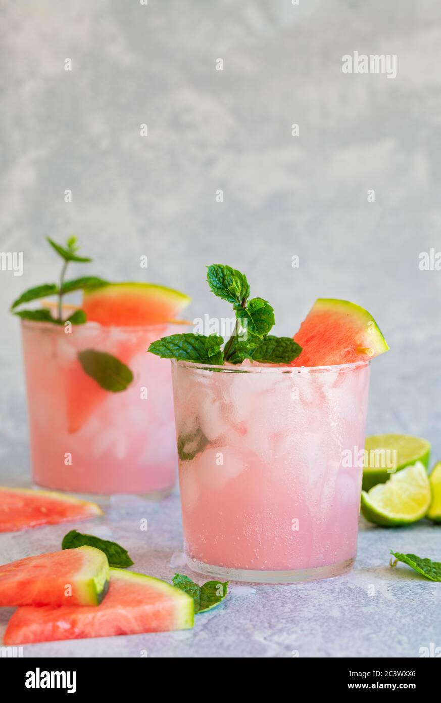 Two pink drink with watermelon and lime, with mint garnish. The drink