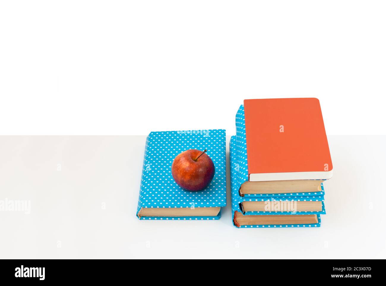 Back to school, pile of books and red apple on the white table. Distance home education. Quarantine concept of stay home Stock Photo