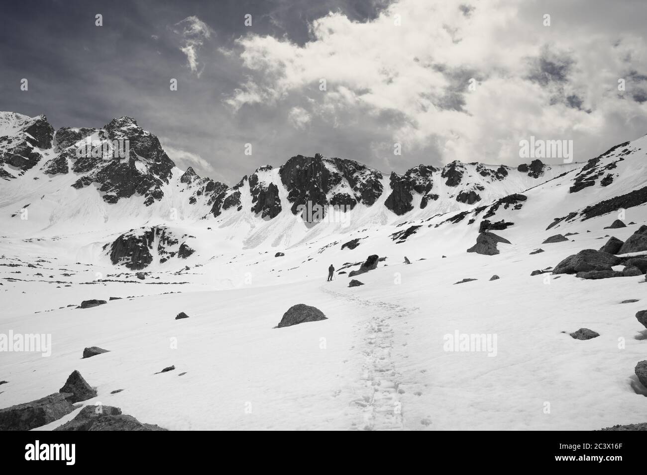 Silhouette of hiker in red on snowy plateau in high mountains at sunny day. Turkey, Kachkar Mountains, highest part of Pontic Mountains. Wide angle vi Stock Photo