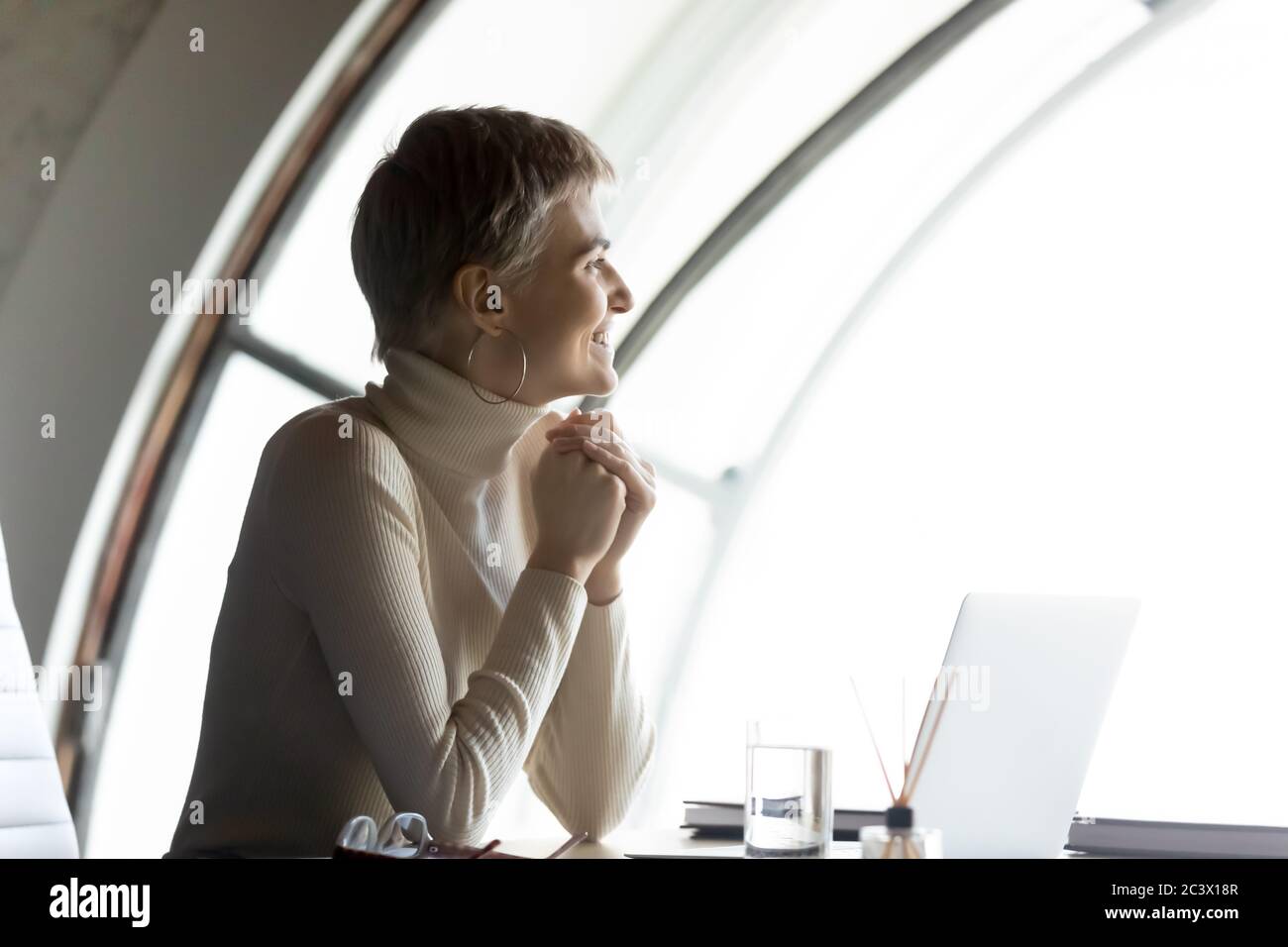 Businesswoman sitting at workplace finish workday look out the window Stock Photo