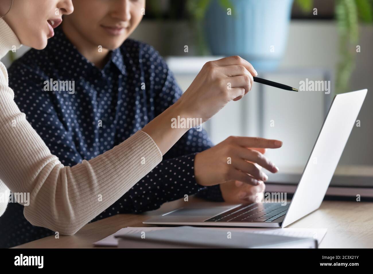 Indian caucasian women colleagues discuss project using laptop closeup Stock Photo