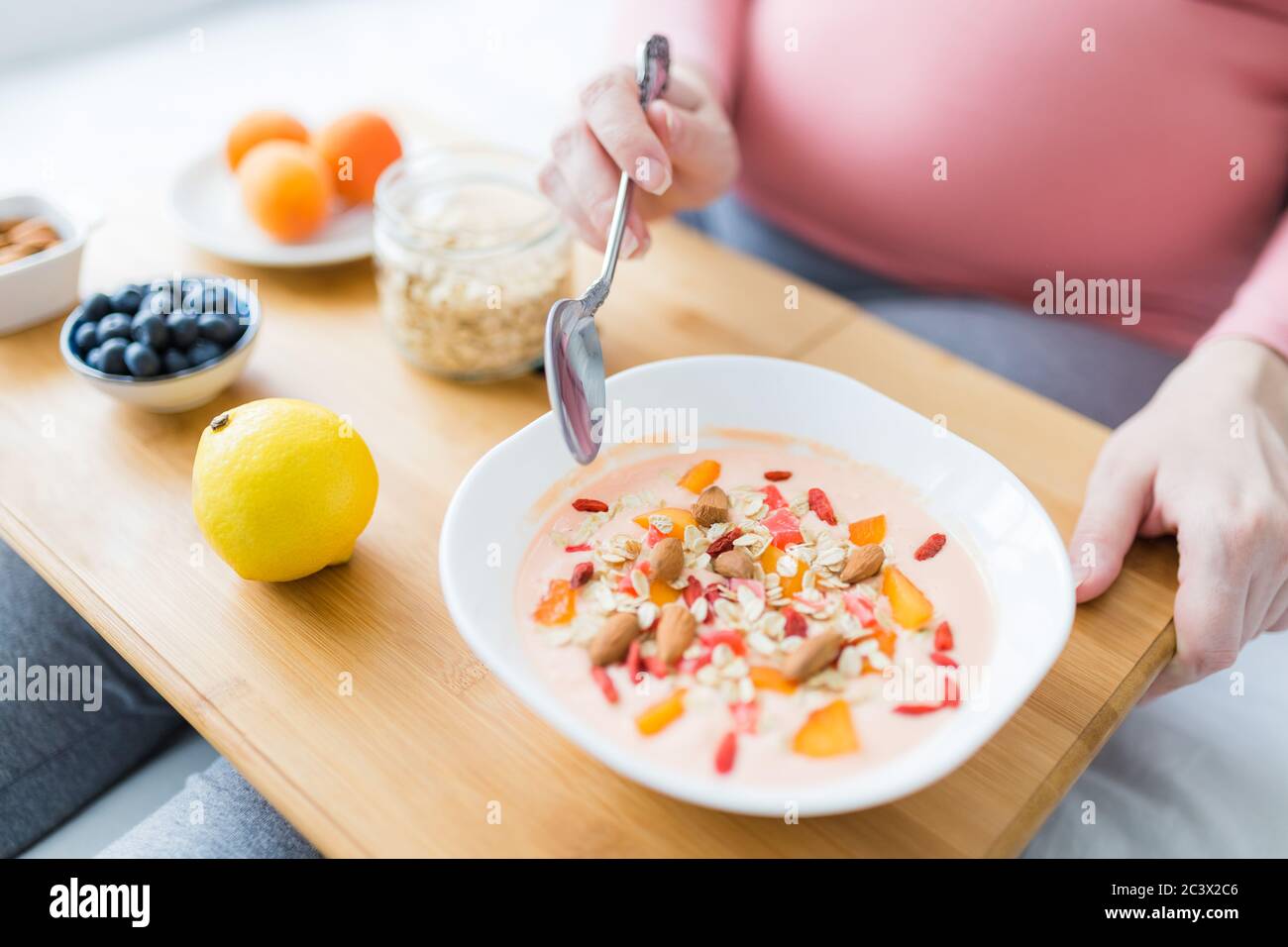Female sitting on sofa and eating fresh muesli. Pregnancy and healthy