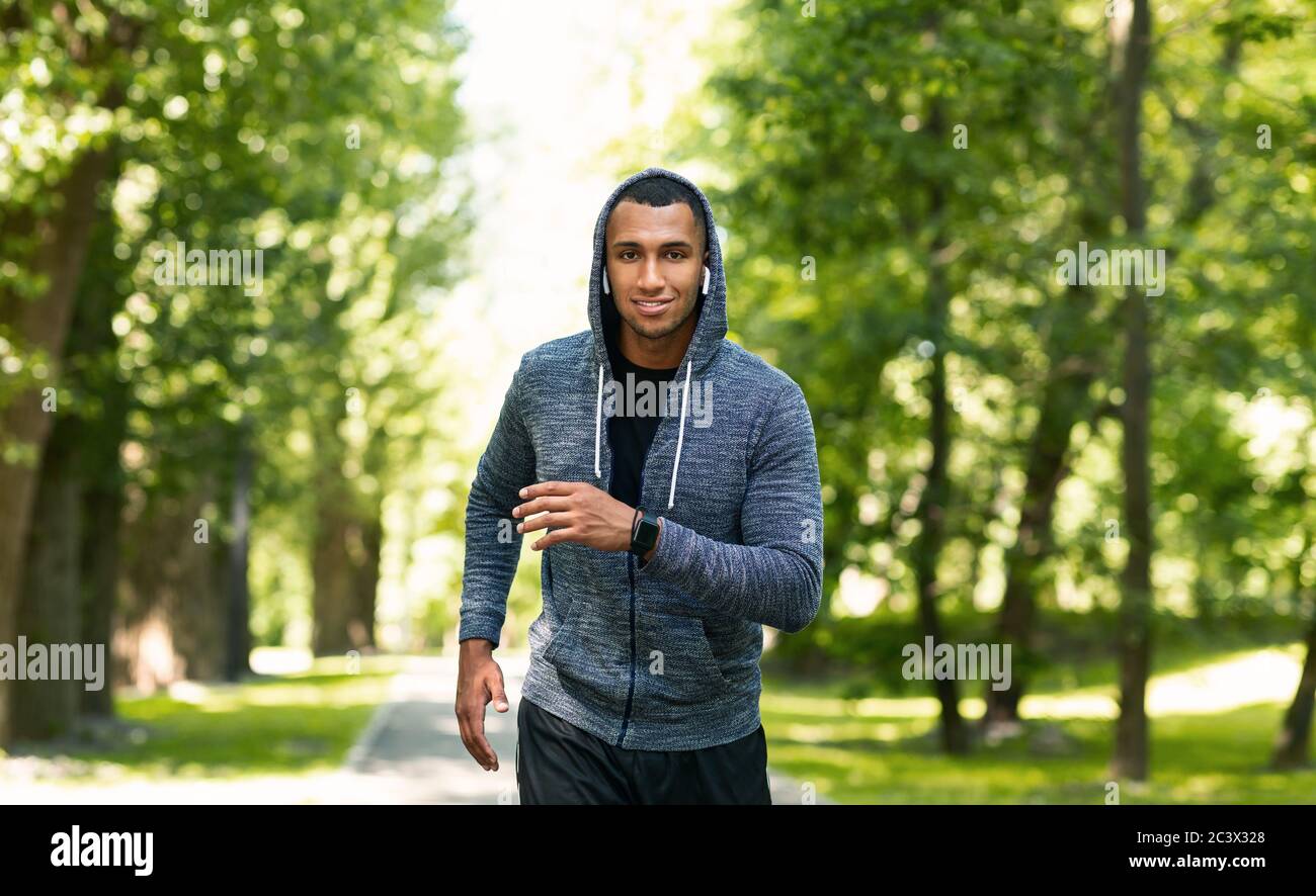 Smiling black athlete training for marathon at green park in summer Stock Photo