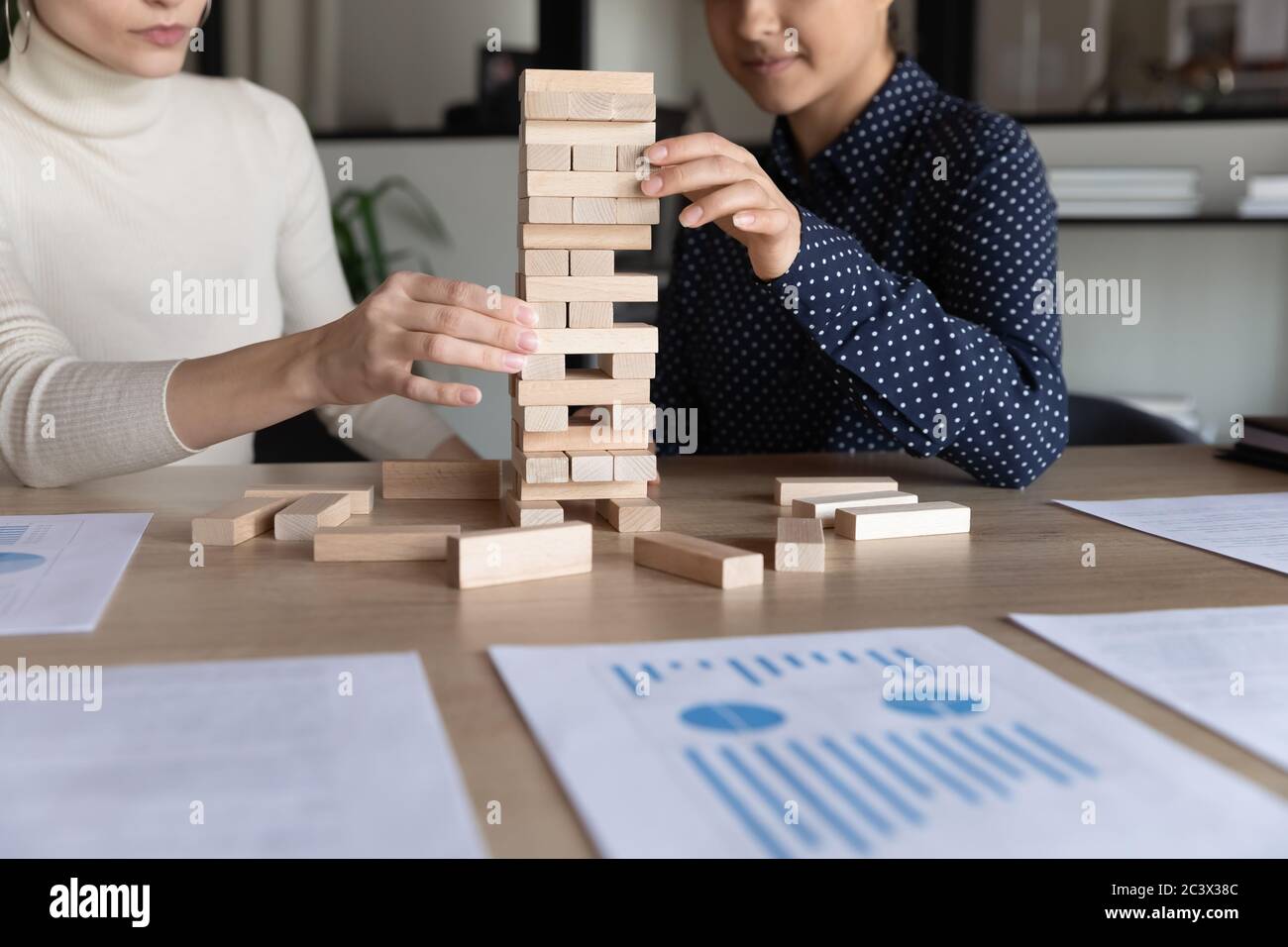 Multiracial businesswomen play build wood block stacking game at