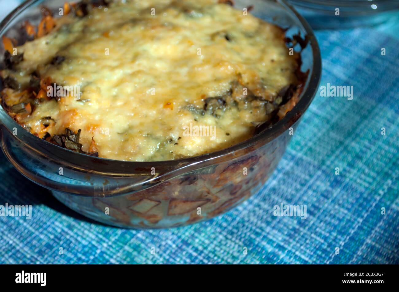 Potato casserole with cheese in  glass  pot on a blue napkin. Lifestyles, homemade Stock Photo