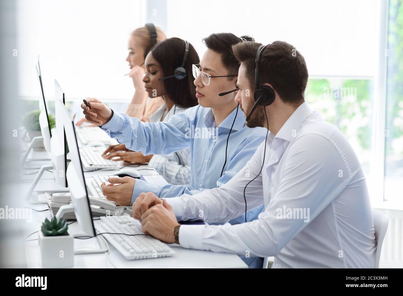 Customer support service. Hotline operator helping his colleague at call  centre office Stock Photo - Alamy