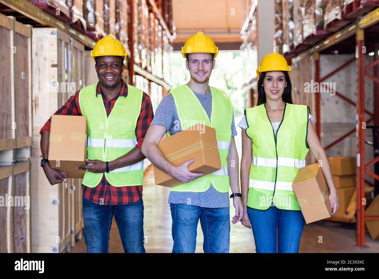Portrait of caucasian white and african black warehouse workers hold cardboard box packaging in warehouse distribution center environment. Using in bu Stock Photo