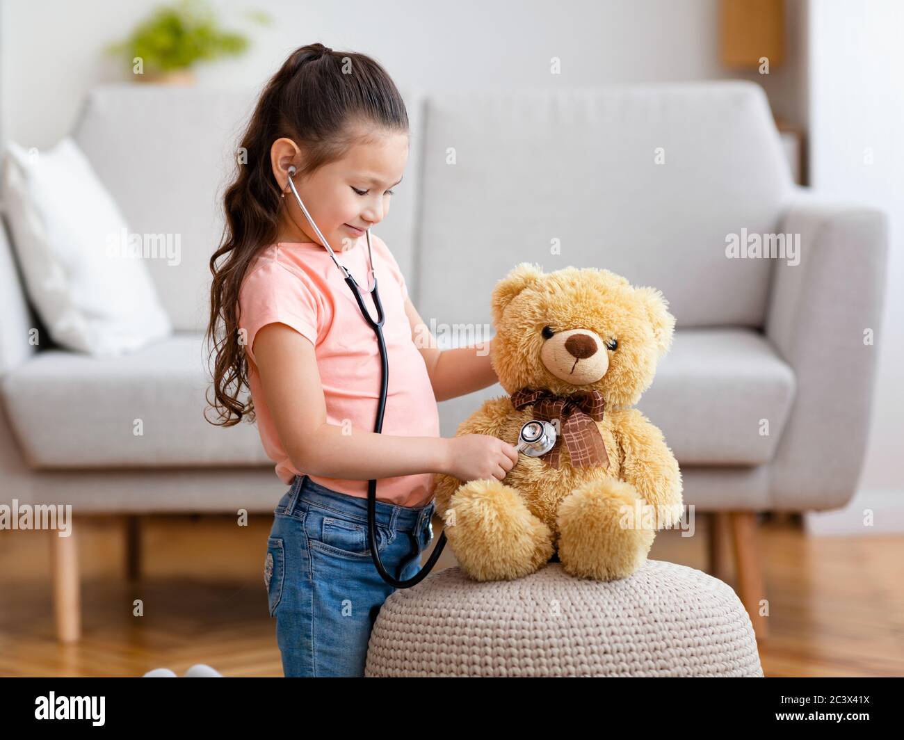 Kid Girl Playing Doctor Using Stethoscope Treating Teddy Bear Indoor Stock Photo