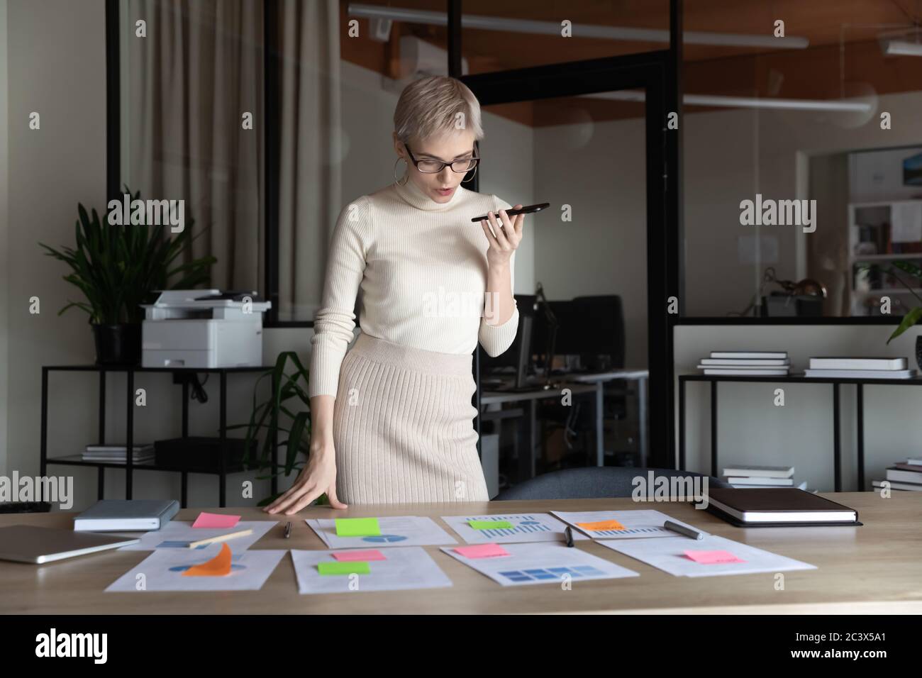 Businesswoman holding smartphone having business talk during project presentation preparation Stock Photo