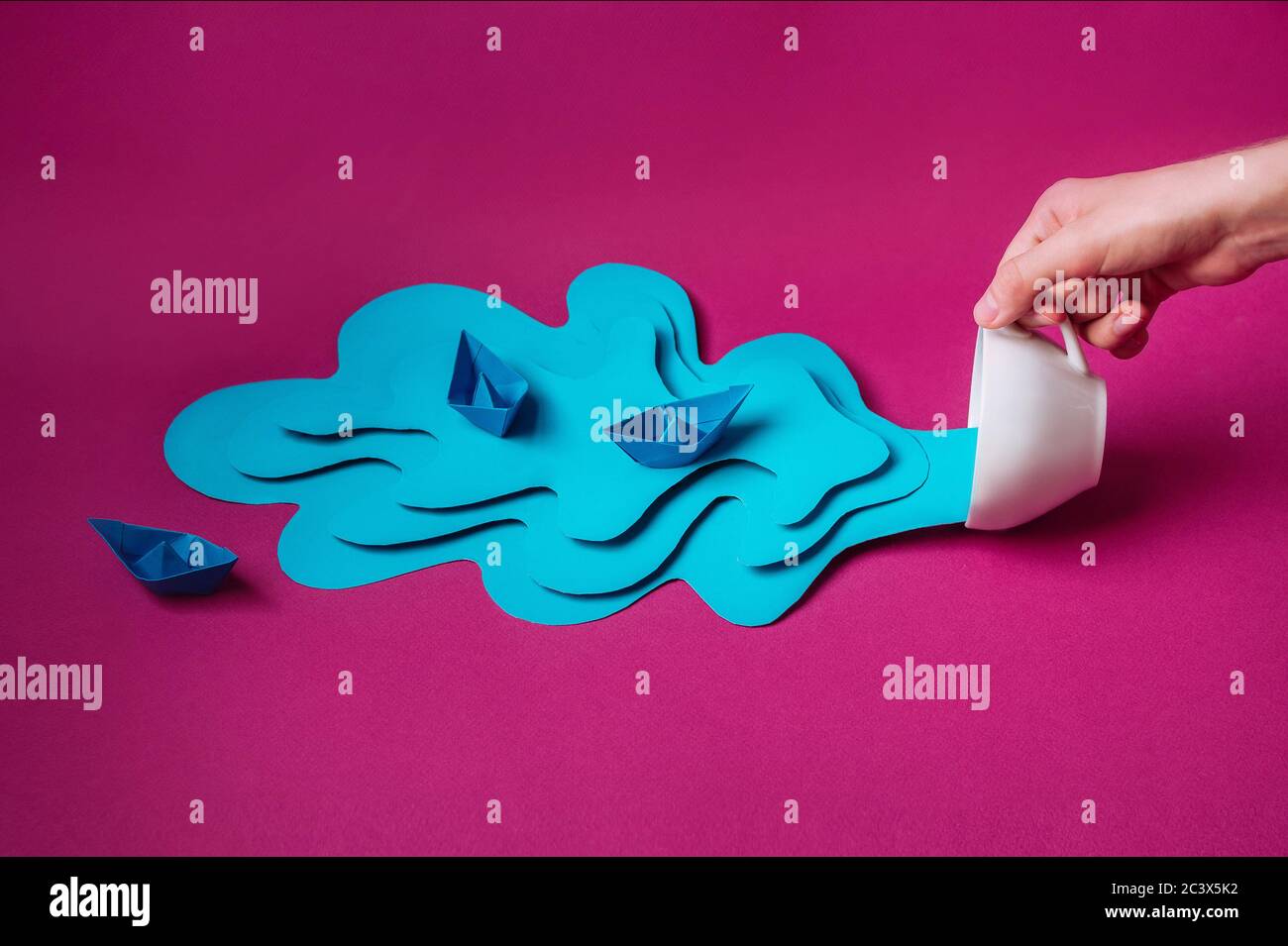Woman's hands holding white tea cup with water and boats made of paper ...