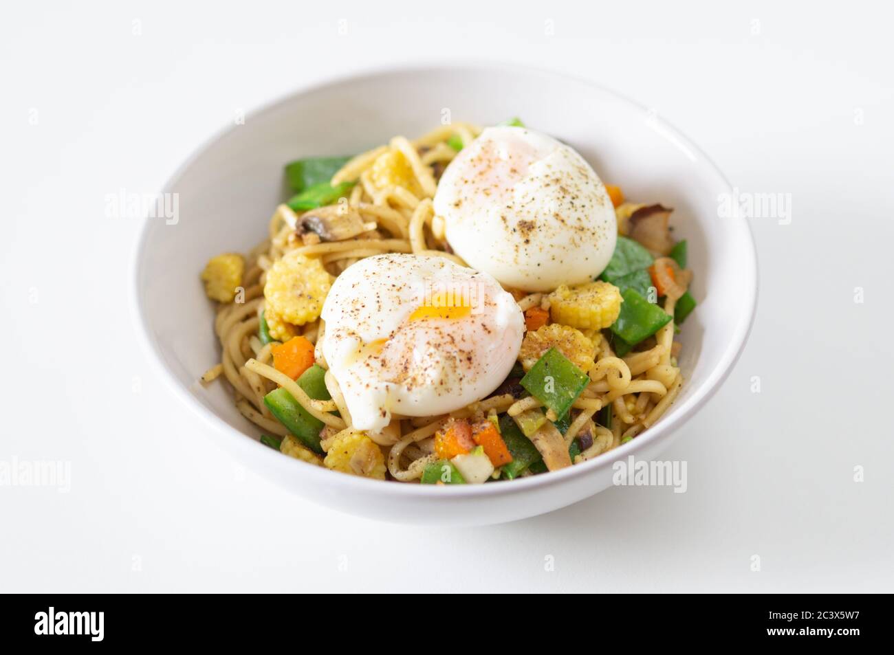 Stir fry with noodles, baby corn, mange tout, mushroom, spring onion and pepper with soft boiled eggs - vegetarian, meat free, healthy, protein Stock Photo
