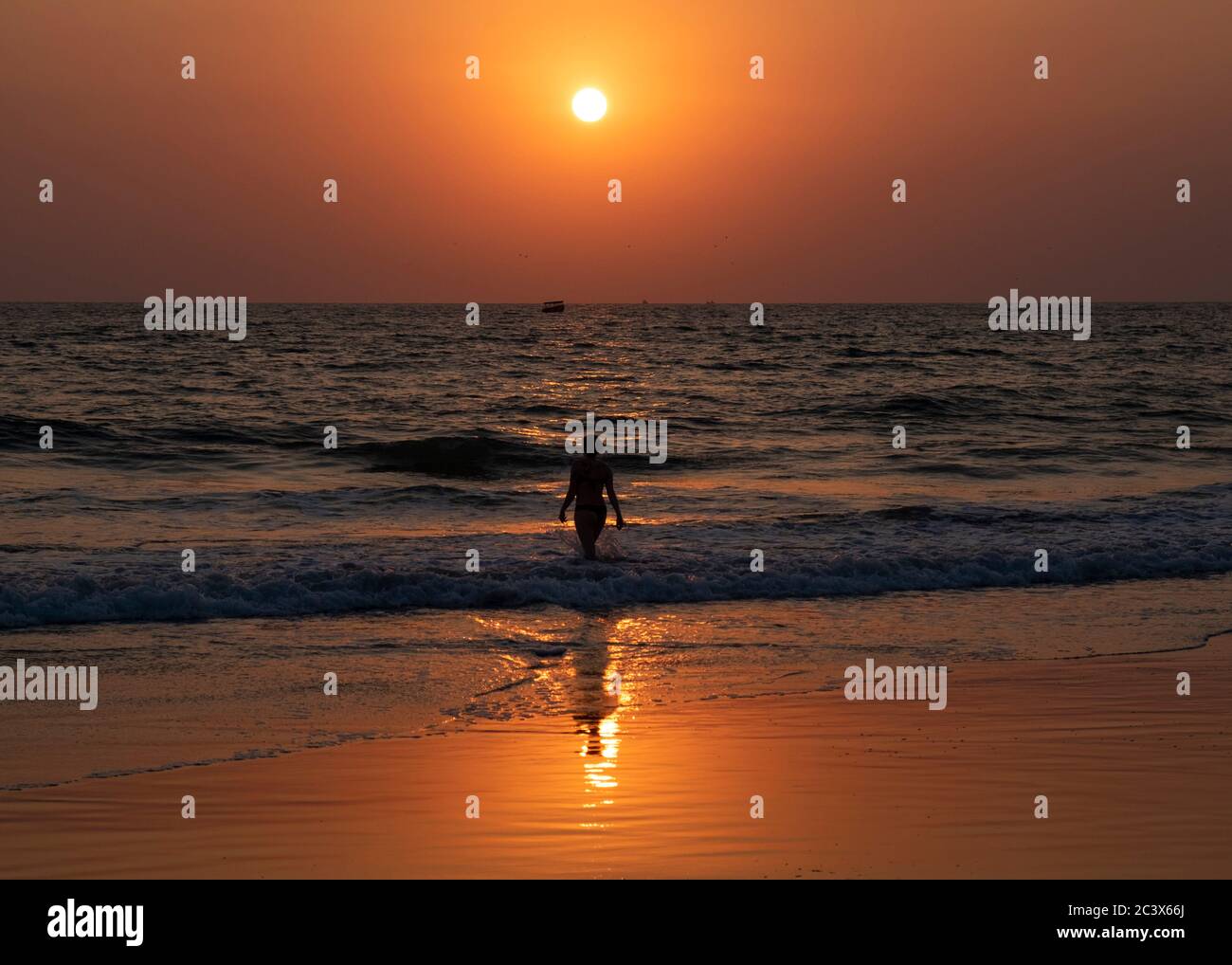 Silhouette of a young woman at sunset in the water at  Majorda beach in Goa, India Stock Photo