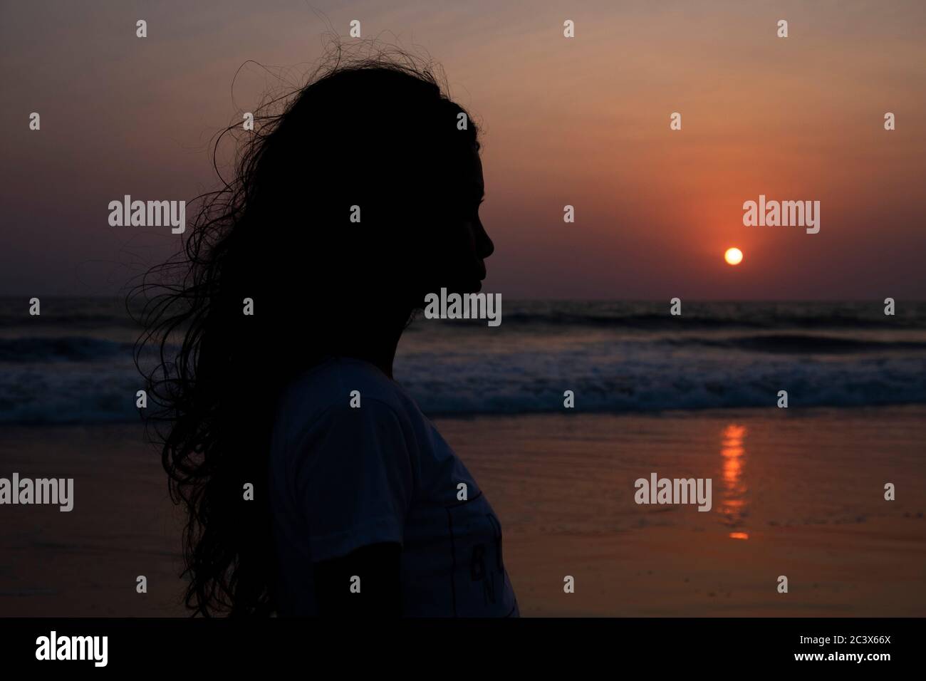 Profile silhouette of young woman at sunset at Majorda beach in Goa, India. Stock Photo