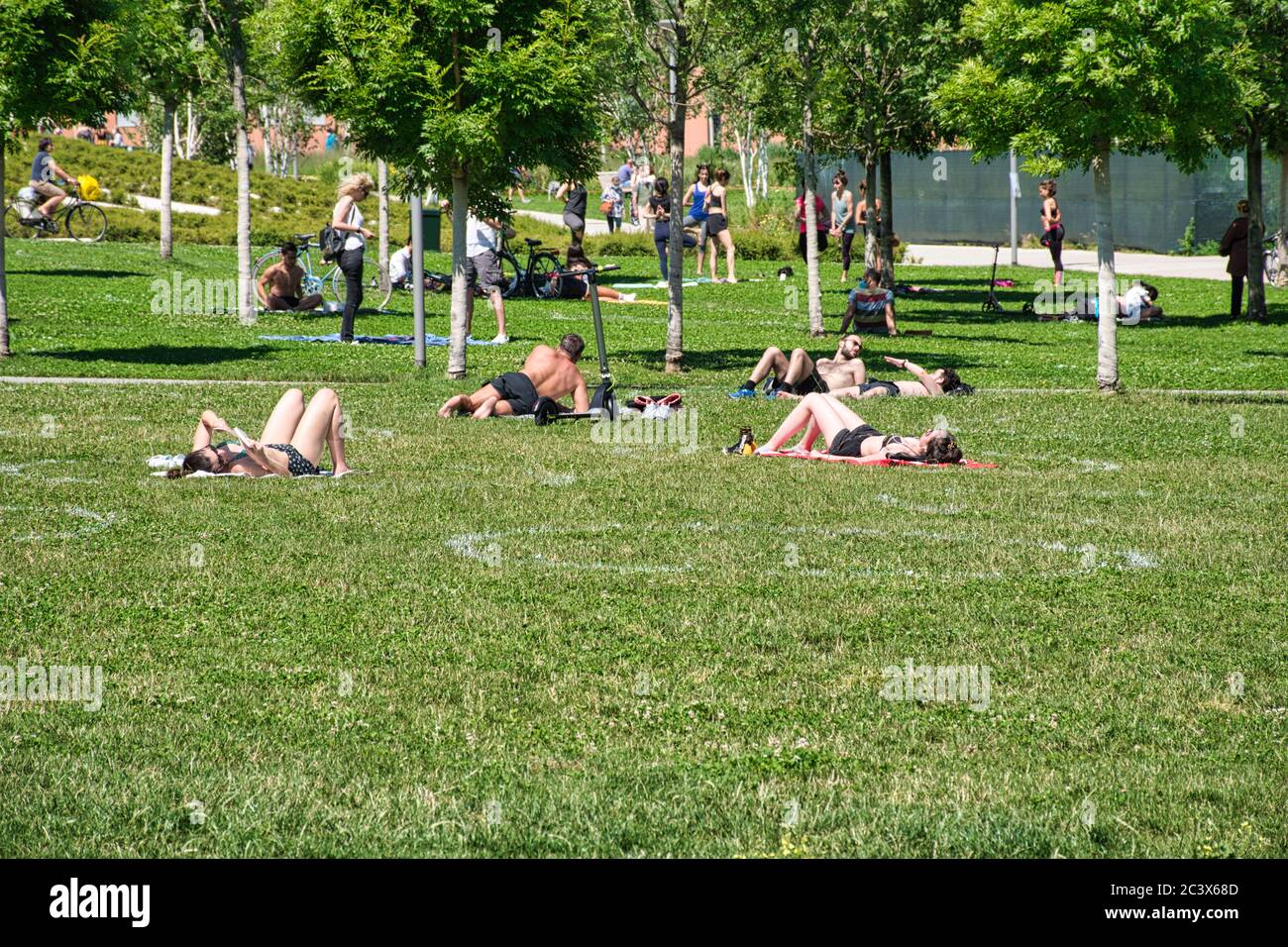 Milan, Italy 06.20.2020: People relaxing and enjoying the sun in Social distancing circles painted on the grass in the new Library Of Trees park in Mi Stock Photo