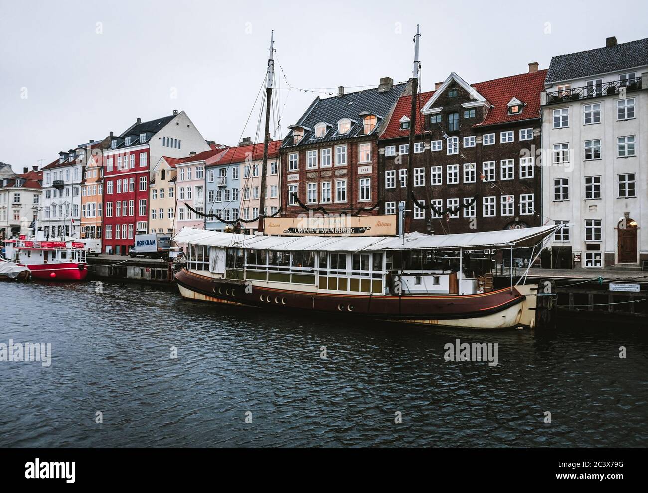 Copenhagen / Denmark - November 2019: Moody landscape at a picturesque Nyhavn harbor in the heart of Copenhagen. Colorful painted buildings and boats Stock Photo