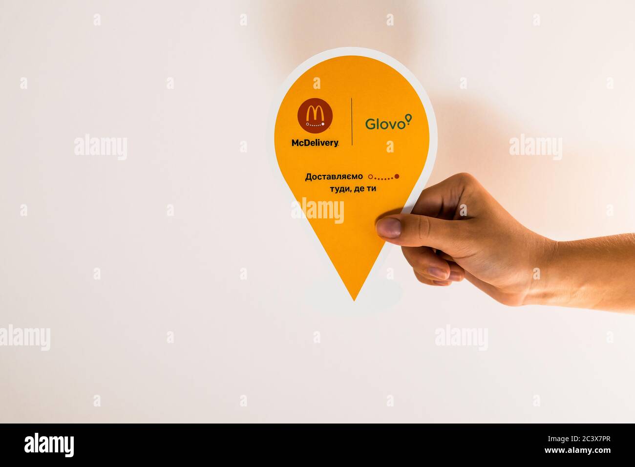 Lviv / Ukraine - April 2020: Glovo delivery service label in a hand against the white wall. Ordering takeaway food from home during social isolation. Stock Photo