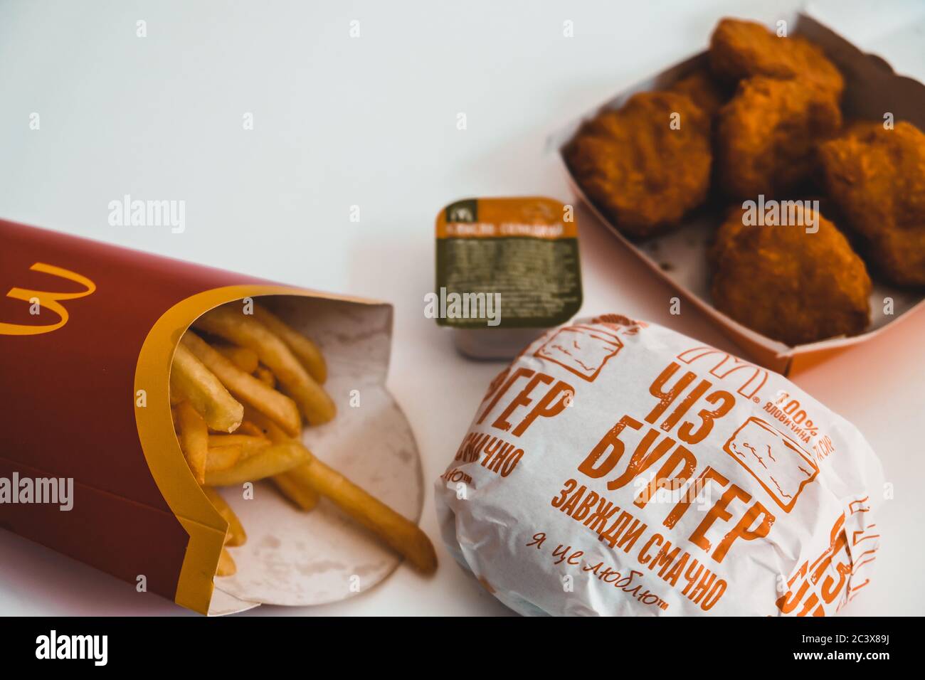 Lviv / Ukraine - April 2020: Whole meal from Ukrainian Mcdonalds on a white table at home. Unhealthy eating during coronavirus outbreak. Takeout food. Stock Photo
