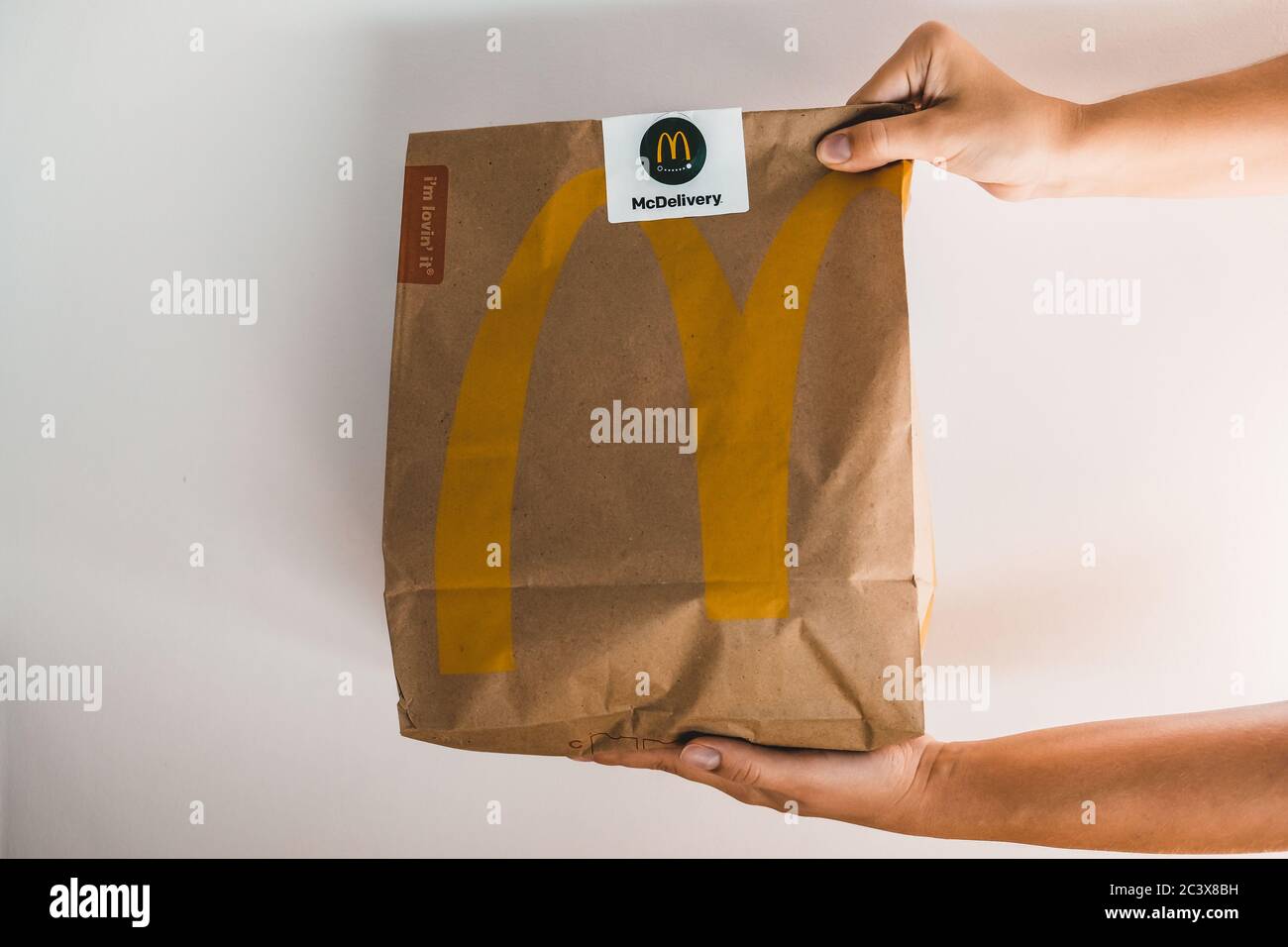 Lviv / Ukraine - April 2020: Two hands giving a paper bag with Mcdonalds takeaway food. Unhealthy eating at home during coronavirus outbreak isolation Stock Photo