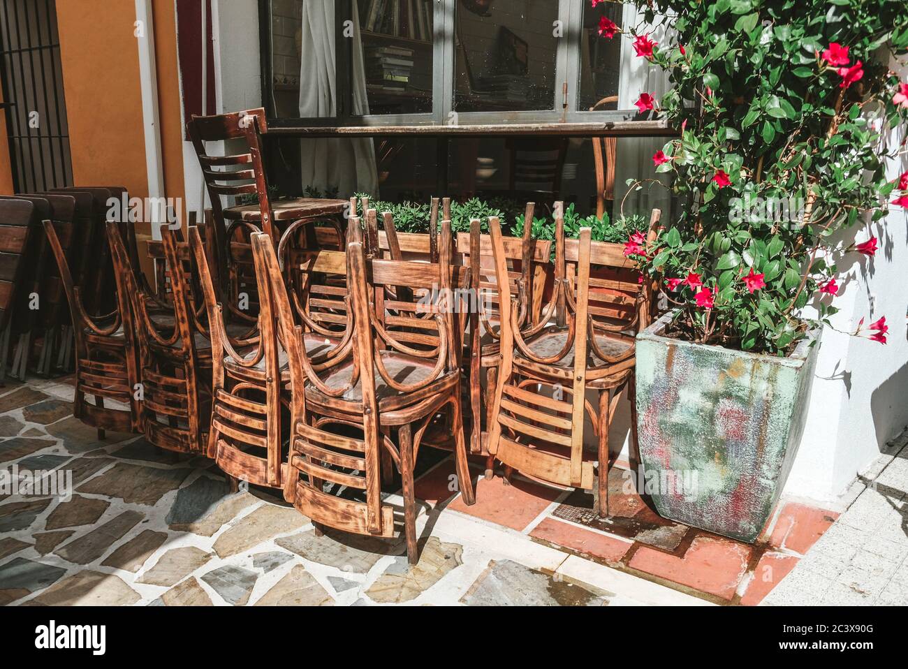 A bunch of stacked chairs near a closed cafe in Spain. Outside view on a sunny day. Early morning, no visitors, tourists around. Empty Spanish street Stock Photo