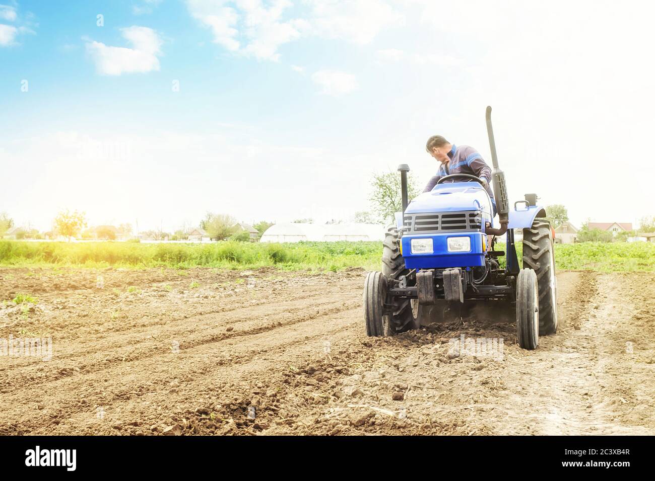 Farmer on a tractor with milling machine loosens, grinds and mixes soil ...