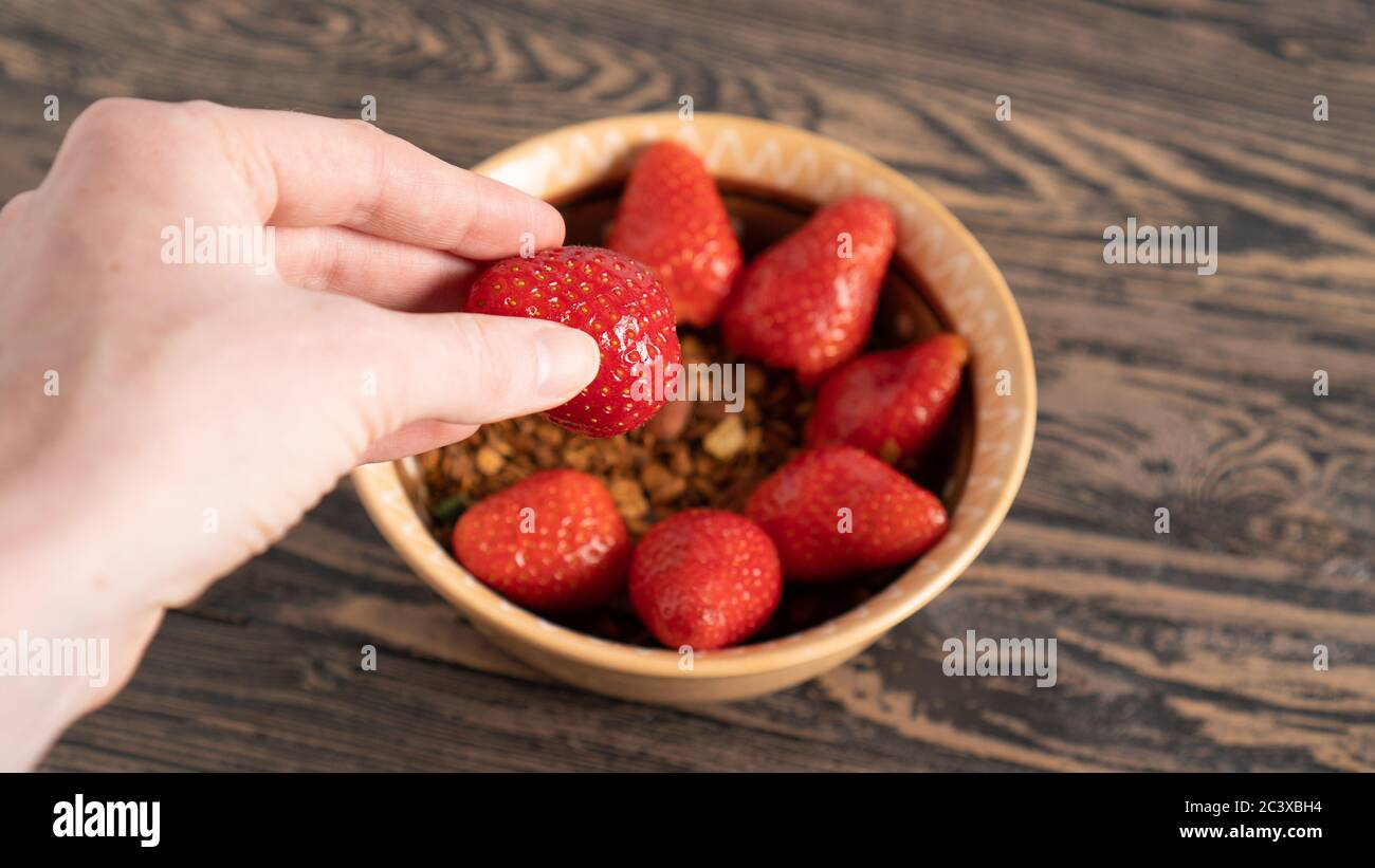 Hand taking strawberry from summer breakfast. Creating delicious, simple and healthy food. Hand holding berry. Sun shape Stock Photo