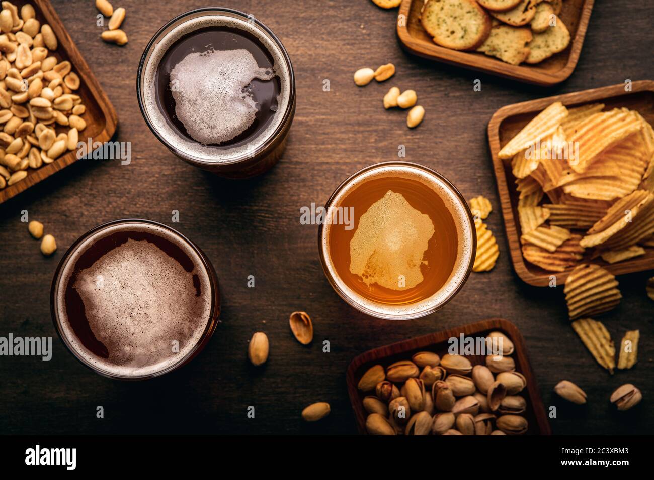 Different types of drink, chips, croutons and nuts in plates and scattered on table Stock Photo
