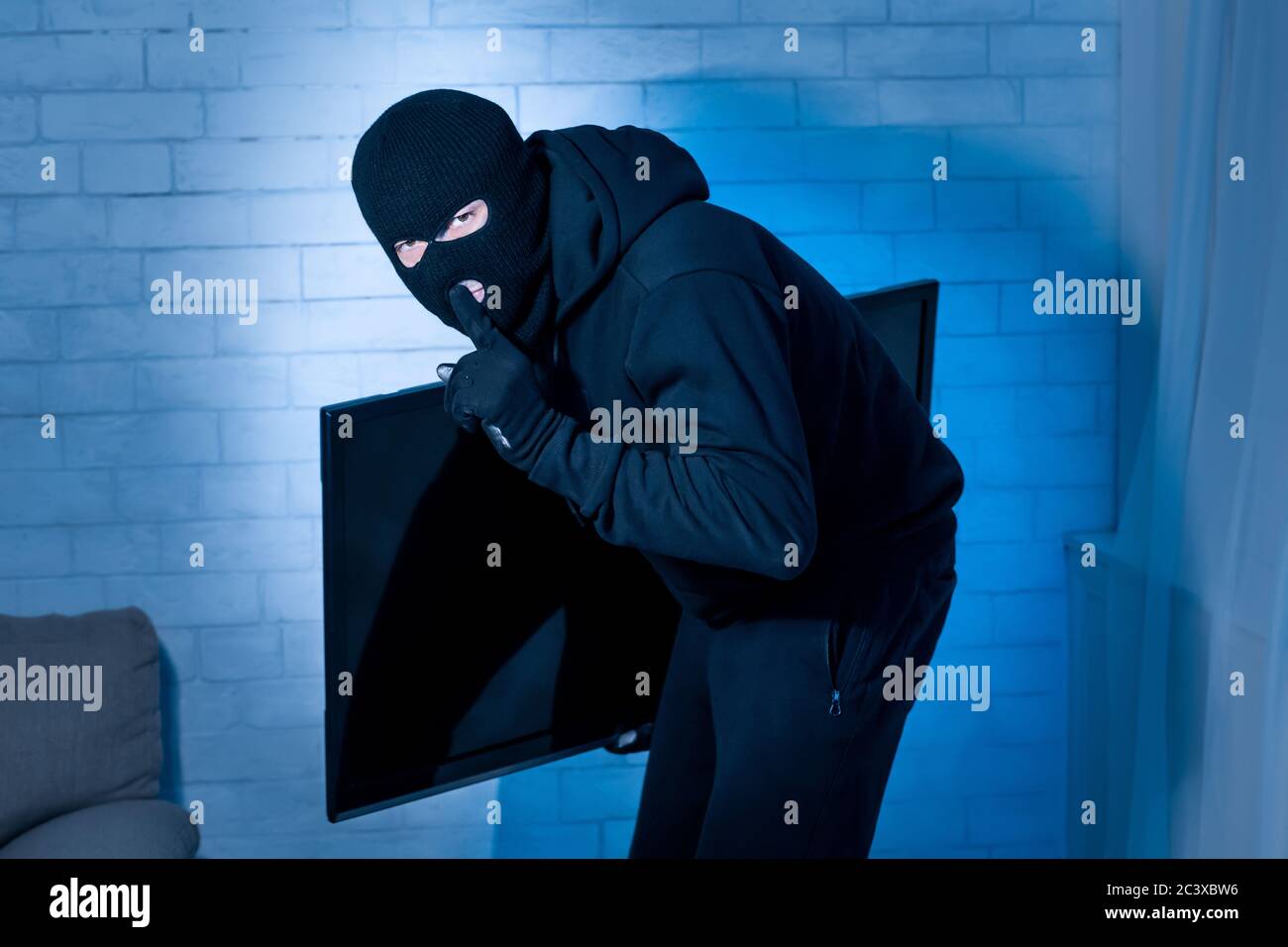 Thief breaking in an apartment and stealing tv Stock Photo