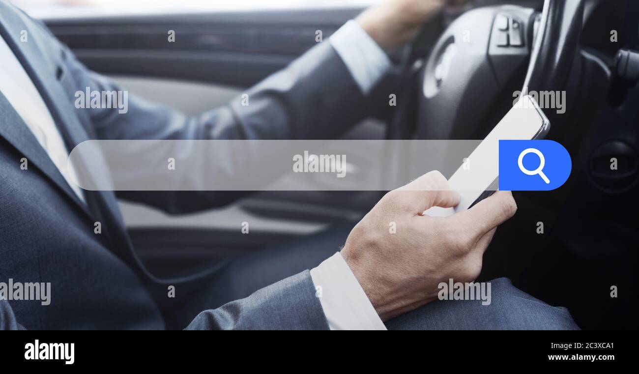 Businessman Using Smartphone While Driving Car With Empty Search Bar On Foreground Stock Photo