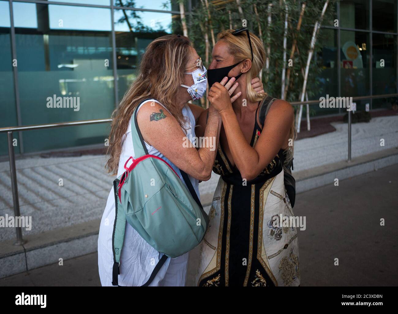 A mother and her daughter wearing face masks are seen kissing each