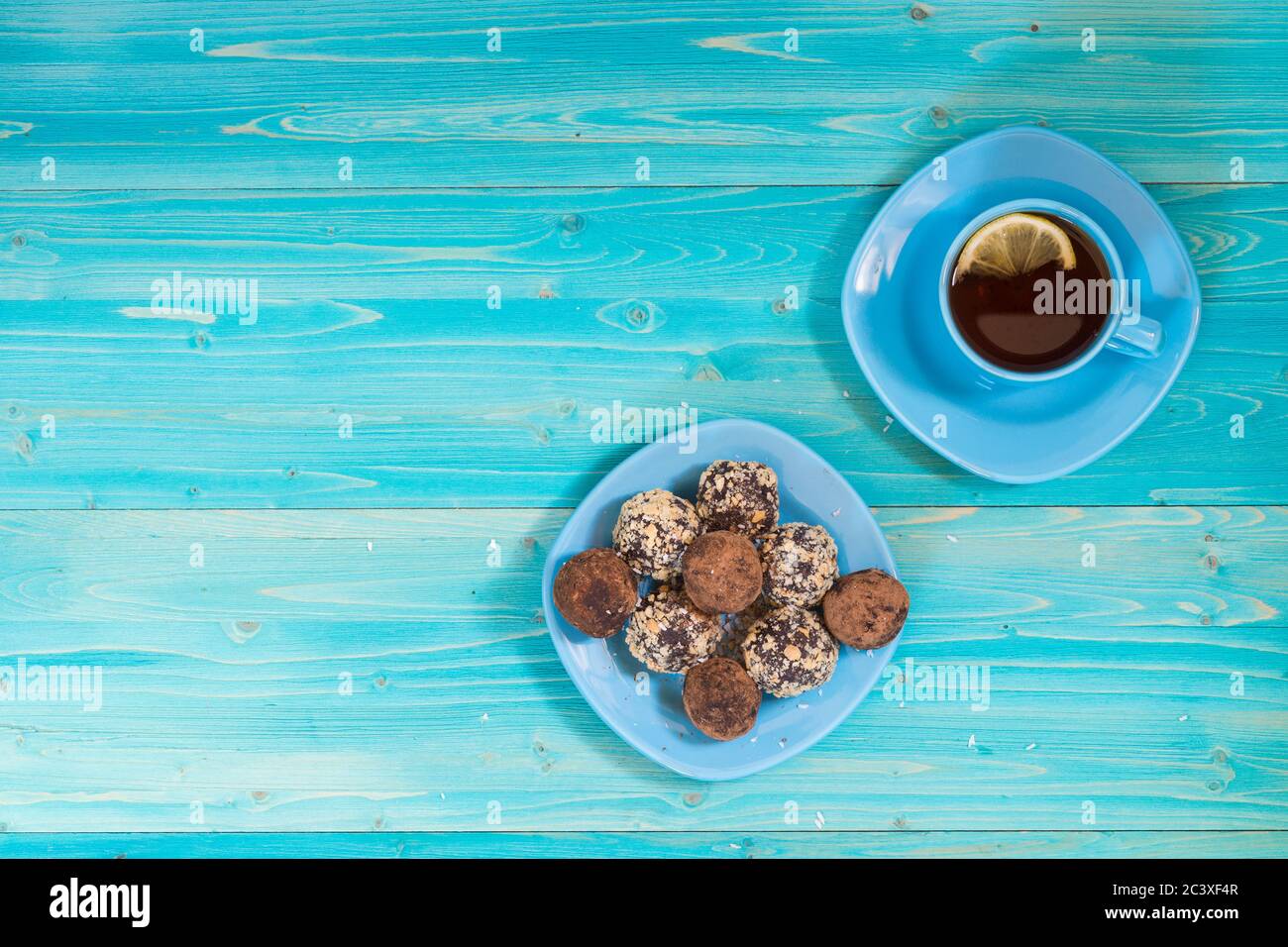 A portion of homemade energy balls and a Cup of tea with lemon on a blue wooden table. Delicious and healthy dessert. Breakfast. Lifestyle. The view f Stock Photo