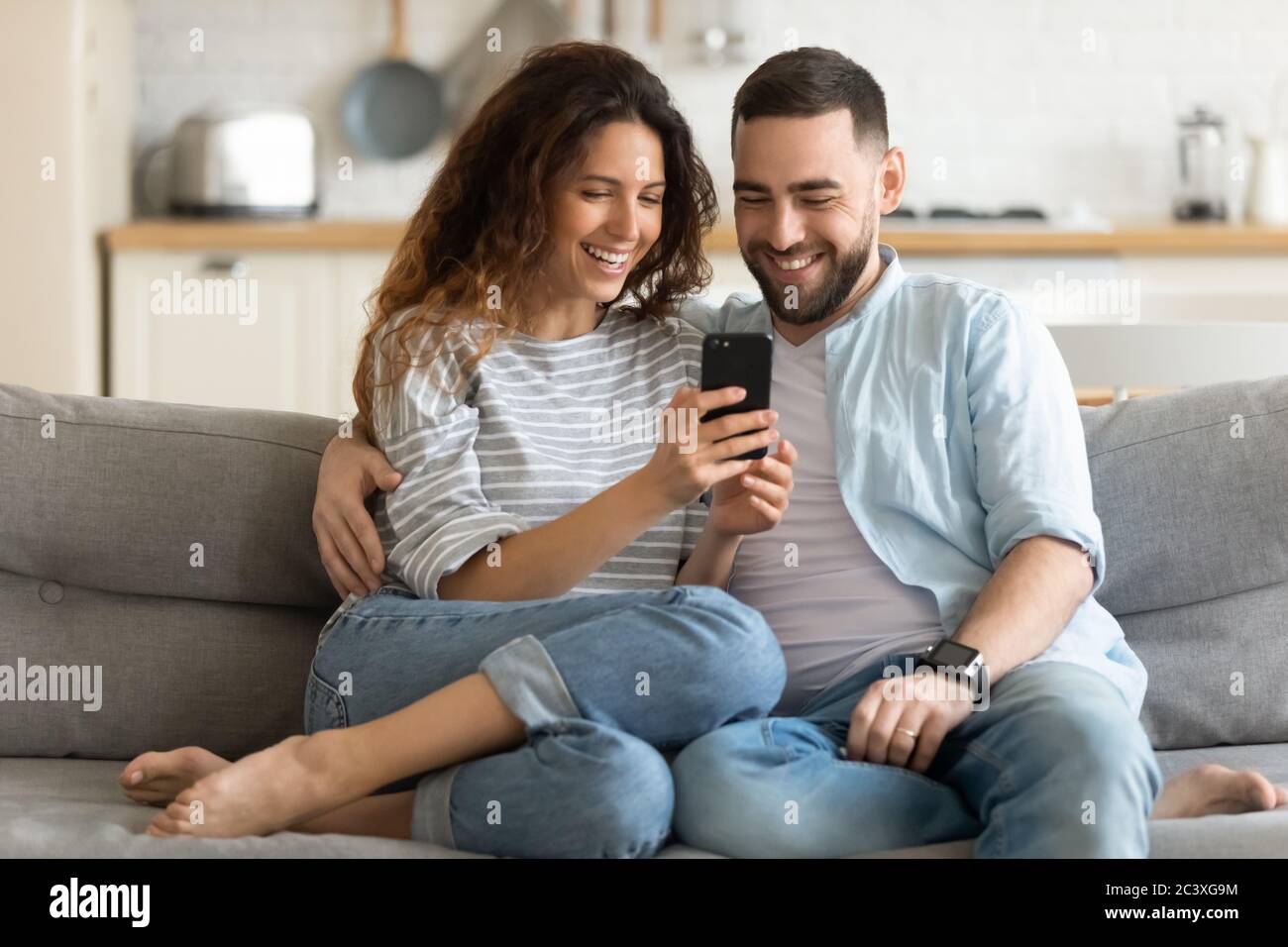 Close up smiling man and woman hugging using smartphone. Stock Photo