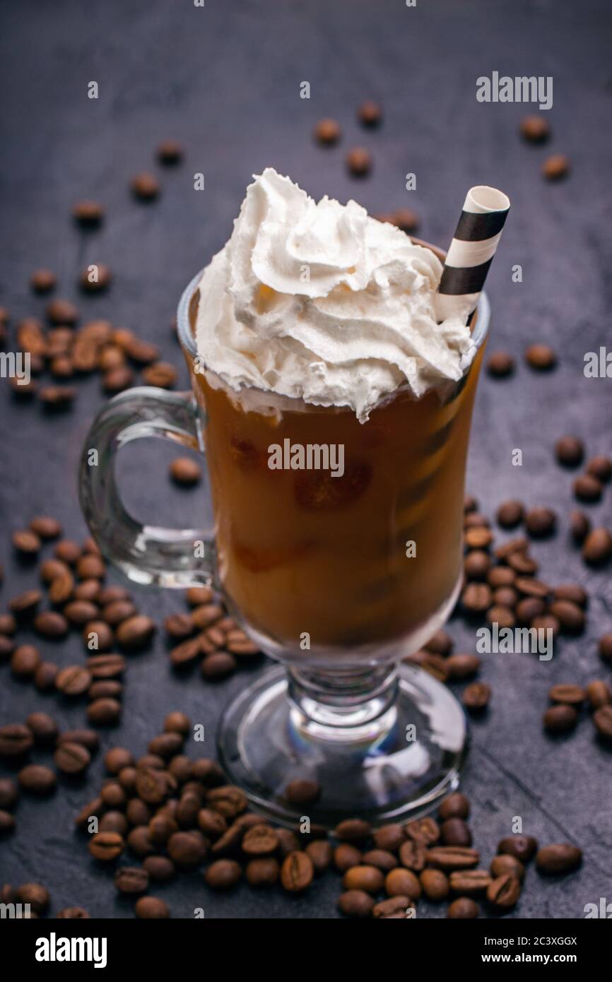 Cold coffee with ice and milk in a glass and whipped cream on top Stock Photo